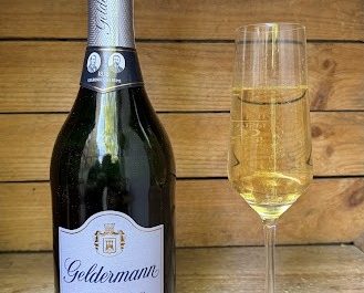Eine Flasche Geldermann Sekt daneben ein Glas mit Sekt.